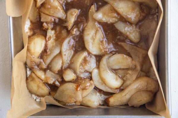 Crust in a baking pan with pear filling on top.