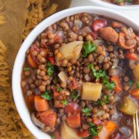 Close up image of two bowls of lentil soup with veggies