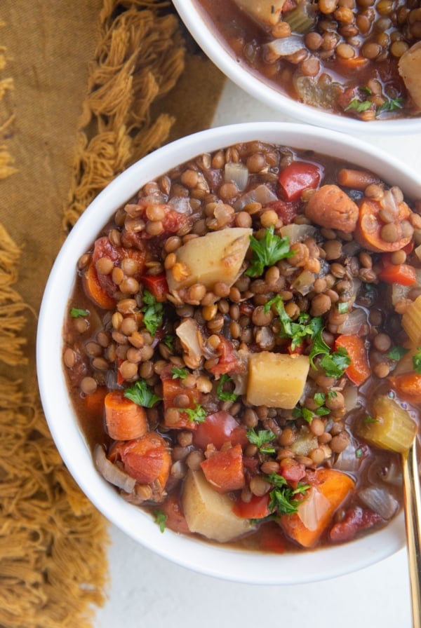 Close up image of two bowls of lentil soup with veggies