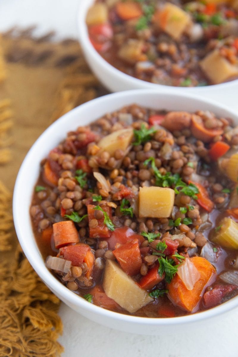 Two white bowls of lentil soup with veggies