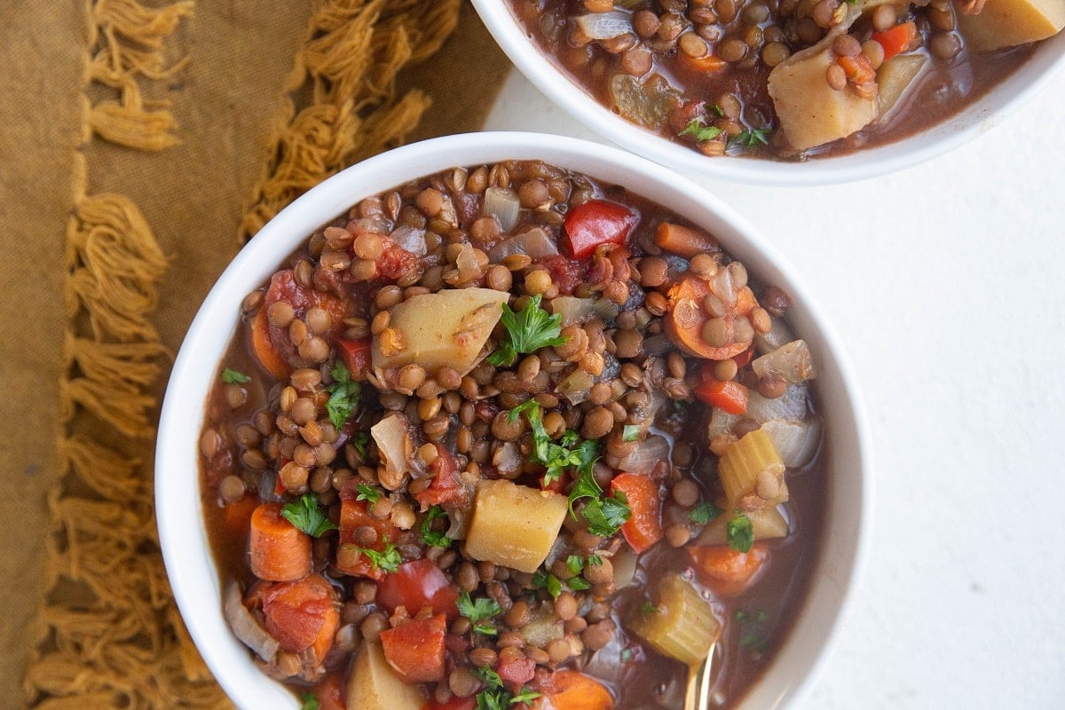 Horizontal image of two white bowls full of lentil stew.