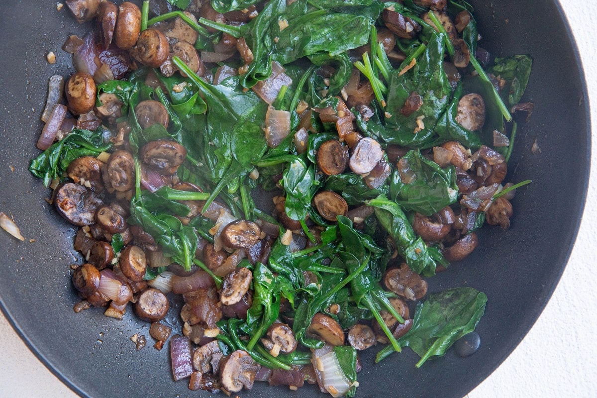 Onion, garlic, mushrooms and spinach cooked in a skillet