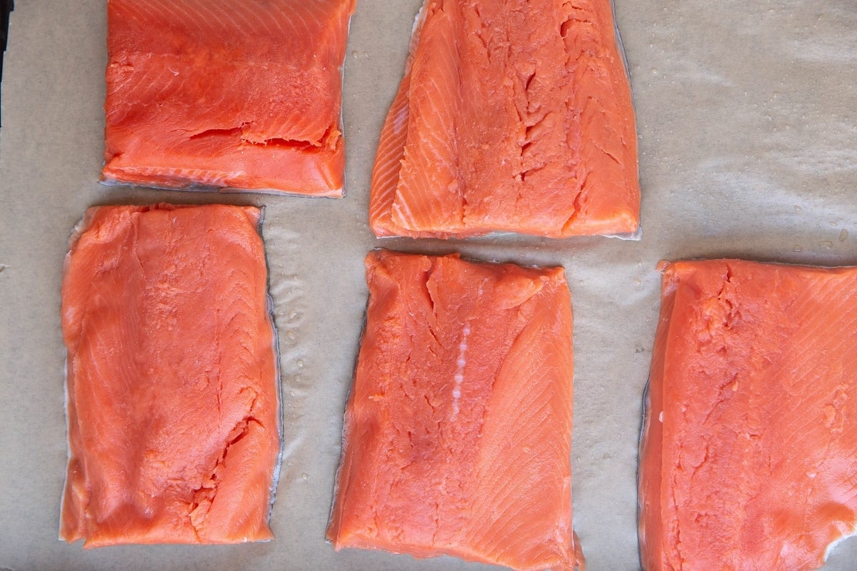 Raw sockeye salmon fillets on a parchment-lined baking sheet.