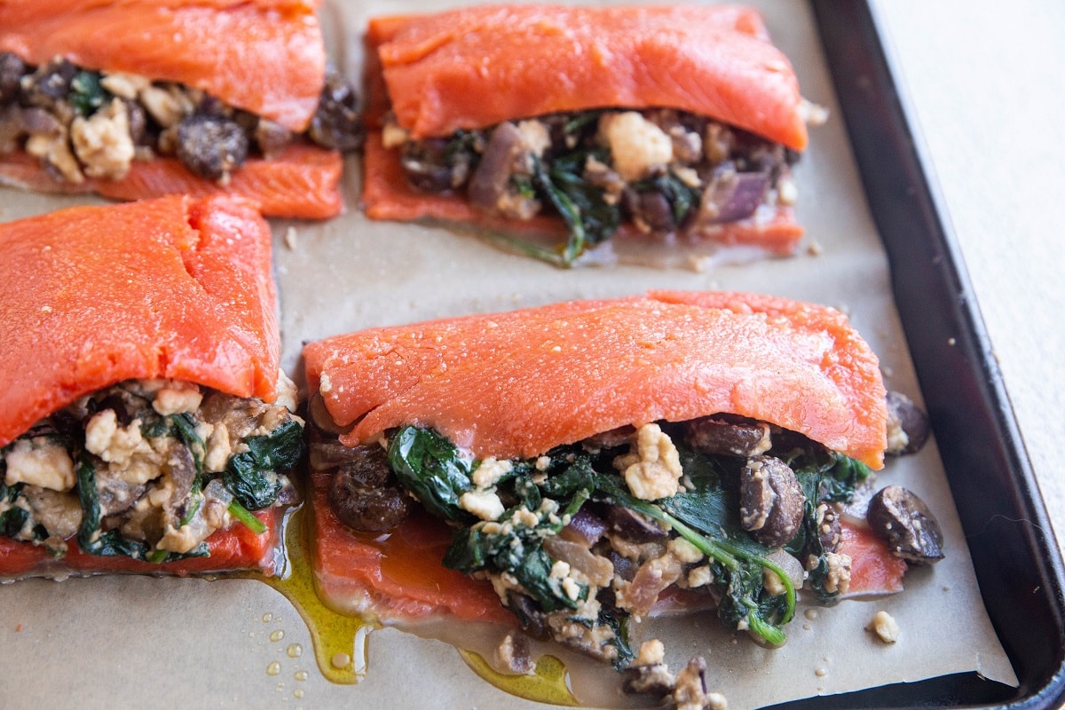 Salmon coated with oil, sprinkled with sea salt, and stuffed, ready to go into the oven.