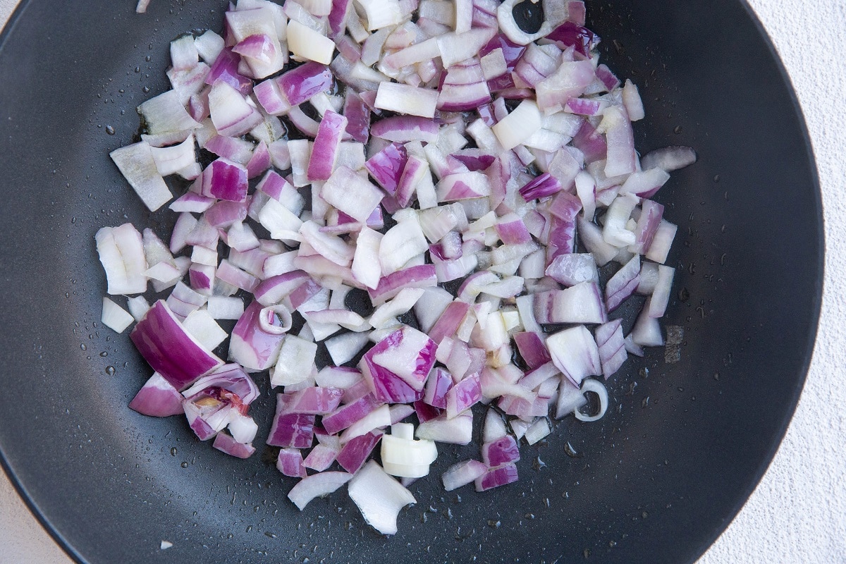 Red onion sautéing in a skillet.