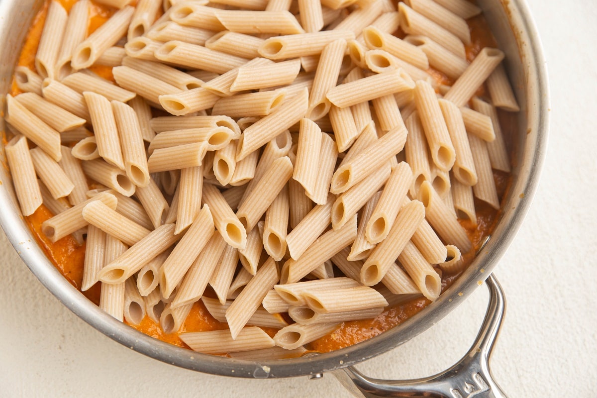 Skillet with chicken and sauce with pasta poured on top