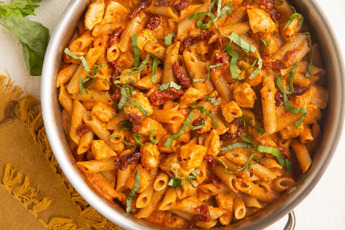 Horizontal top down photo of a skillet of chicken pasta.