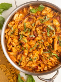 Stainless steel skillet with chicken pasta with sun dried tomato cream sauce.