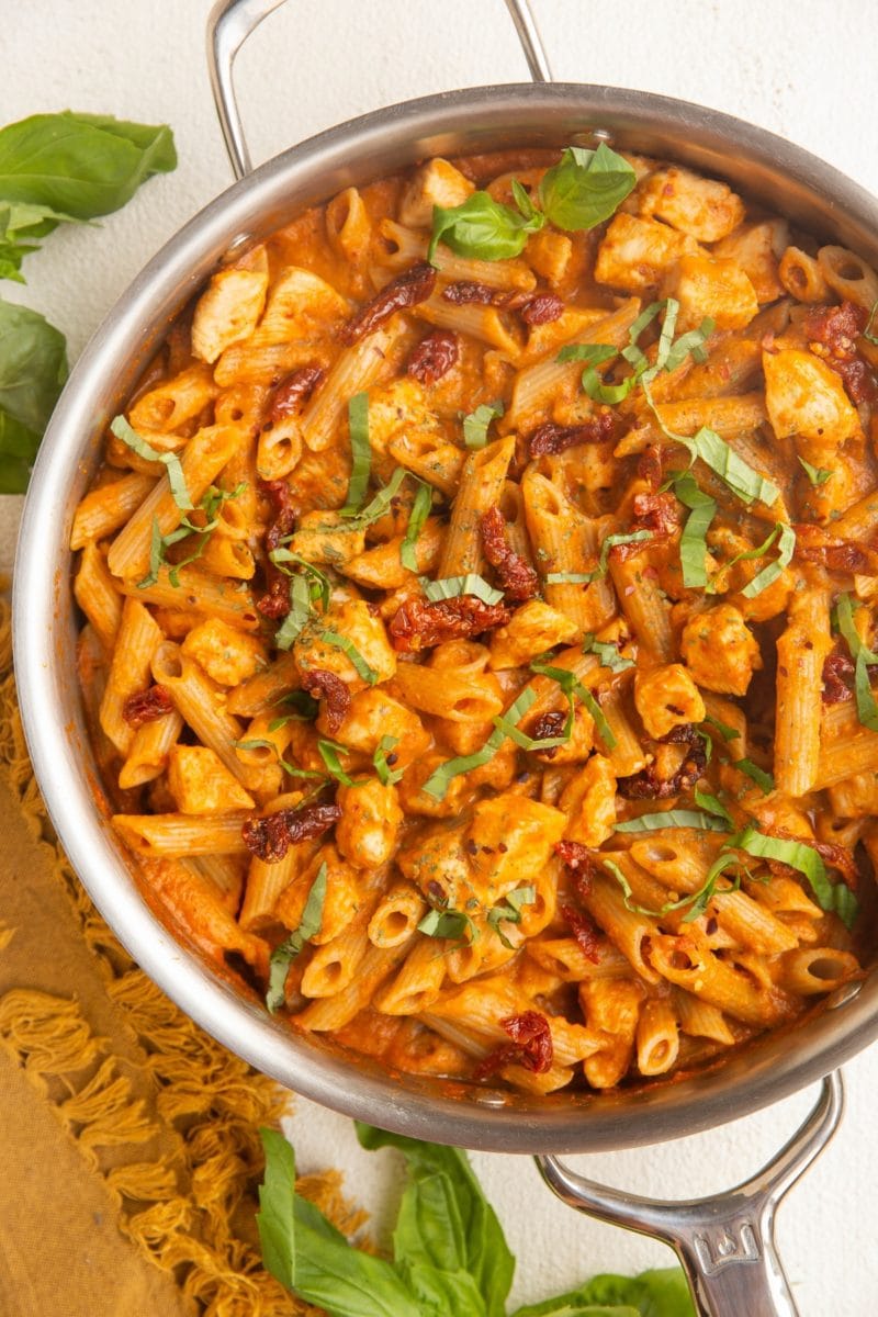 Stainless steel skillet with chicken pasta with sun dried tomato cream sauce.