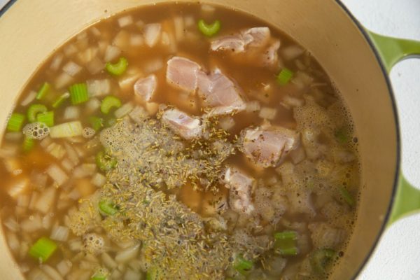 Raw chopped chicken and dried herbs added to the pot