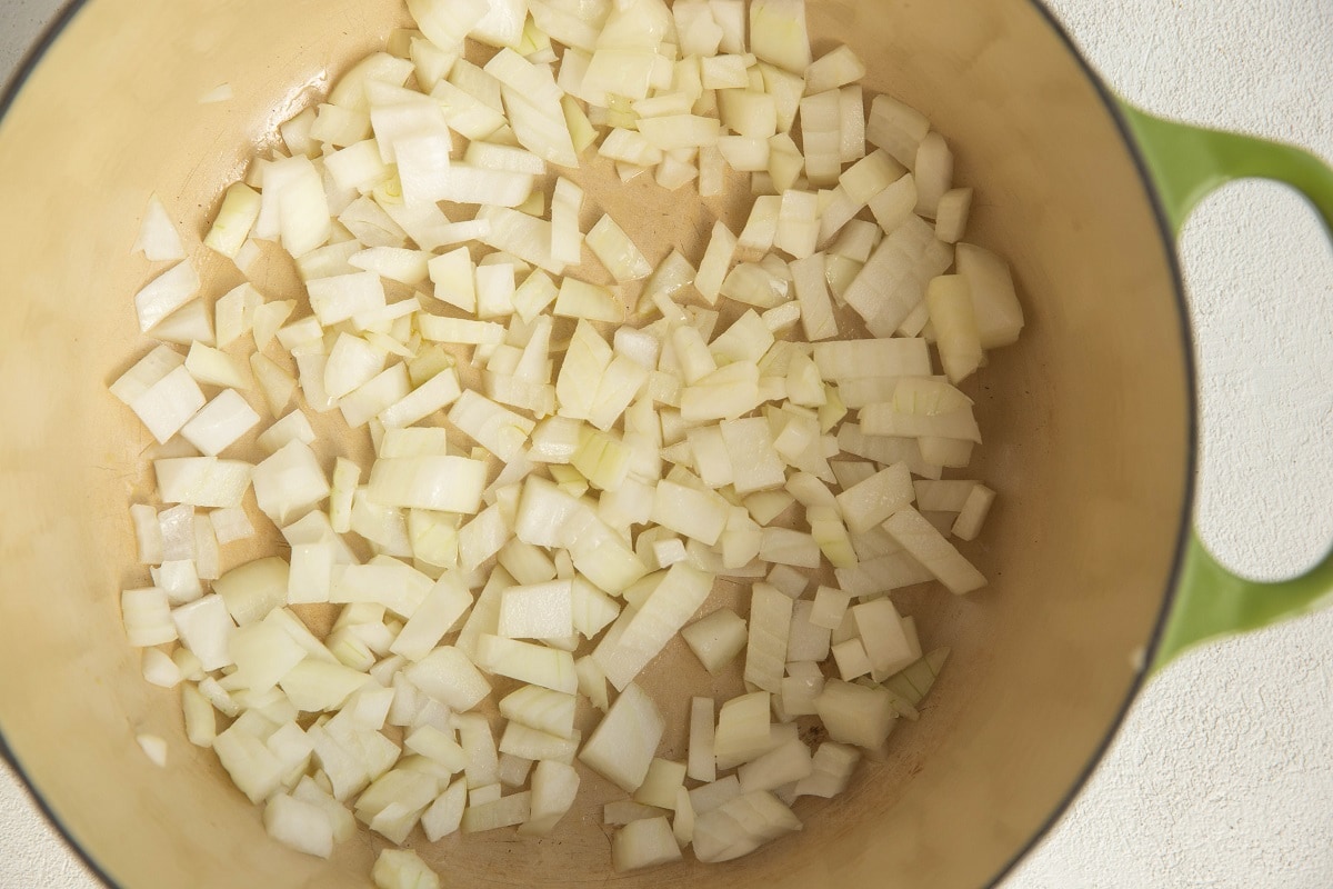 Large pot with onion sautéing inside for soup