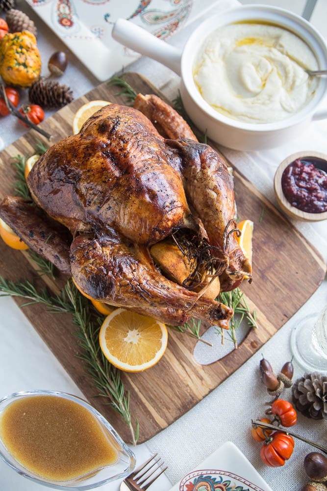 Whole Thanksgiving Turkey on a large cutting board with side dishes to the side.