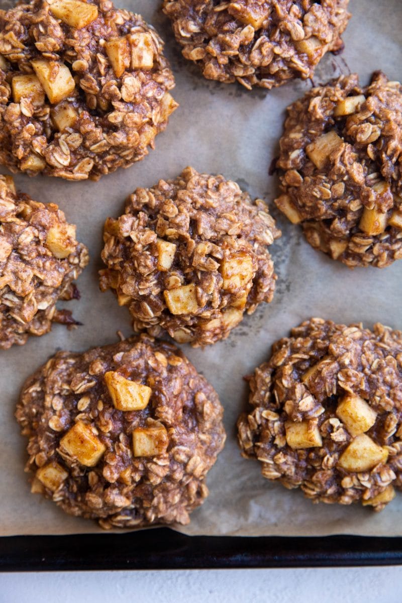 Baking sheet lined with parchment paper with baked apple oatmeal cookies fresh out of the oven.
