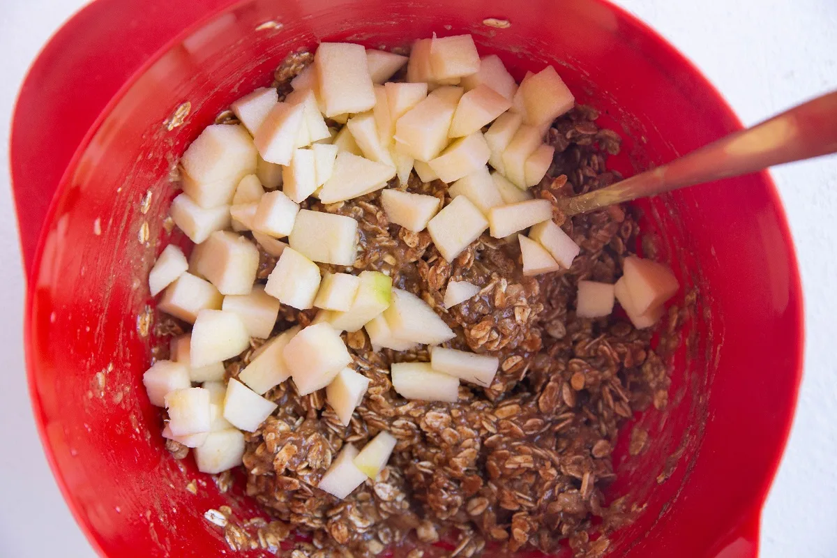 Apple chunks in a mixing bowl with cookie dough, ready to be mixed in.