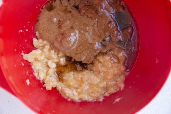 Mashed banana, almond butter, and pure maple syrup in a mixing bowl.