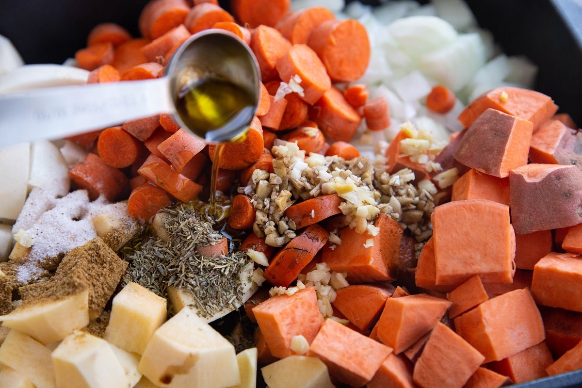 Pouring olive oil into the casserole dish with the vegetables.
