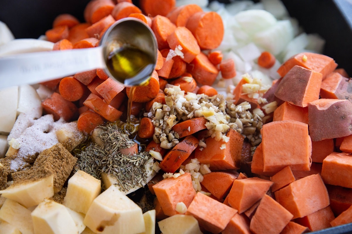 Pouring olive oil into the casserole dish with the vegetables.