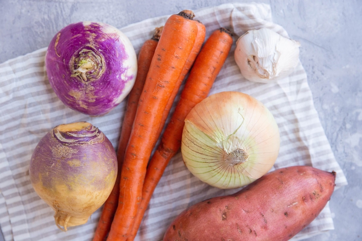 root vegetables sitting on top of a kitchen towel, ready to be chopped up.