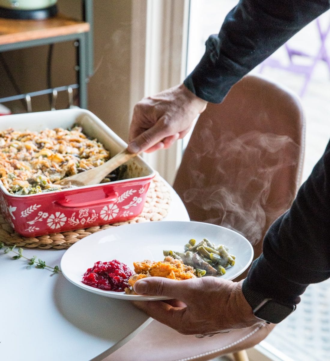 Person holding a plate serving themselves Thanksgiving side dishes