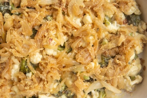 Creamy broccoli and cauliflower with caramelized onion topping spread evenly over it.