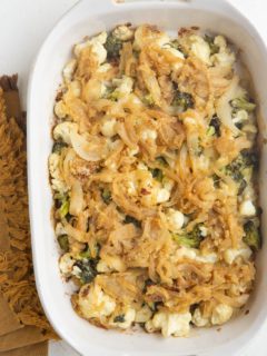 Full casserole dish of broccoli cauliflower casserole with caramelized onions on top.