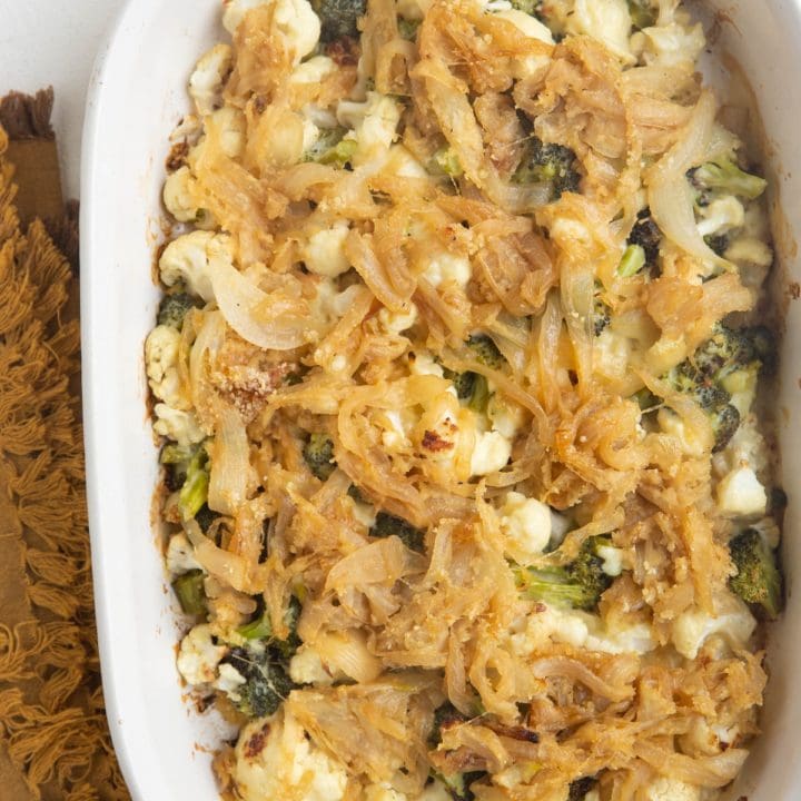 Full casserole dish of broccoli cauliflower casserole with caramelized onions on top.