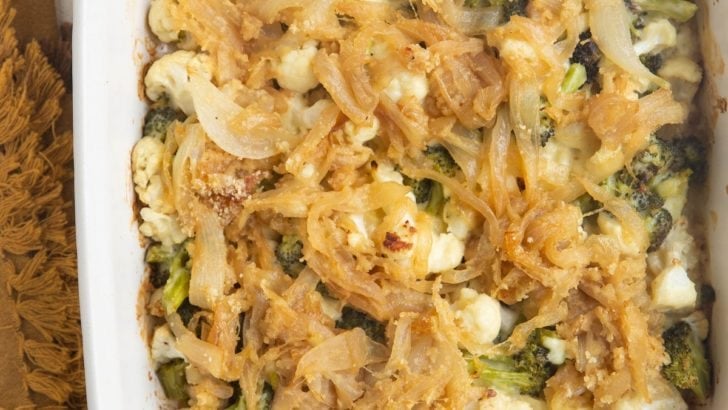 Full casserole dish of broccoli cauliflower casserole with caramelized onions on top.