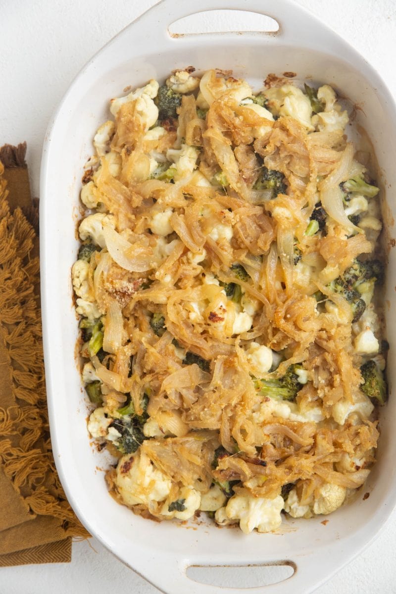 Full casserole dish of broccoli cauliflower casserole with caramelized onions on top.