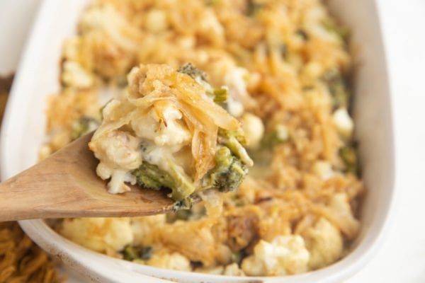 Horizontal photo of wooden spoon taking a scoop of casserole.