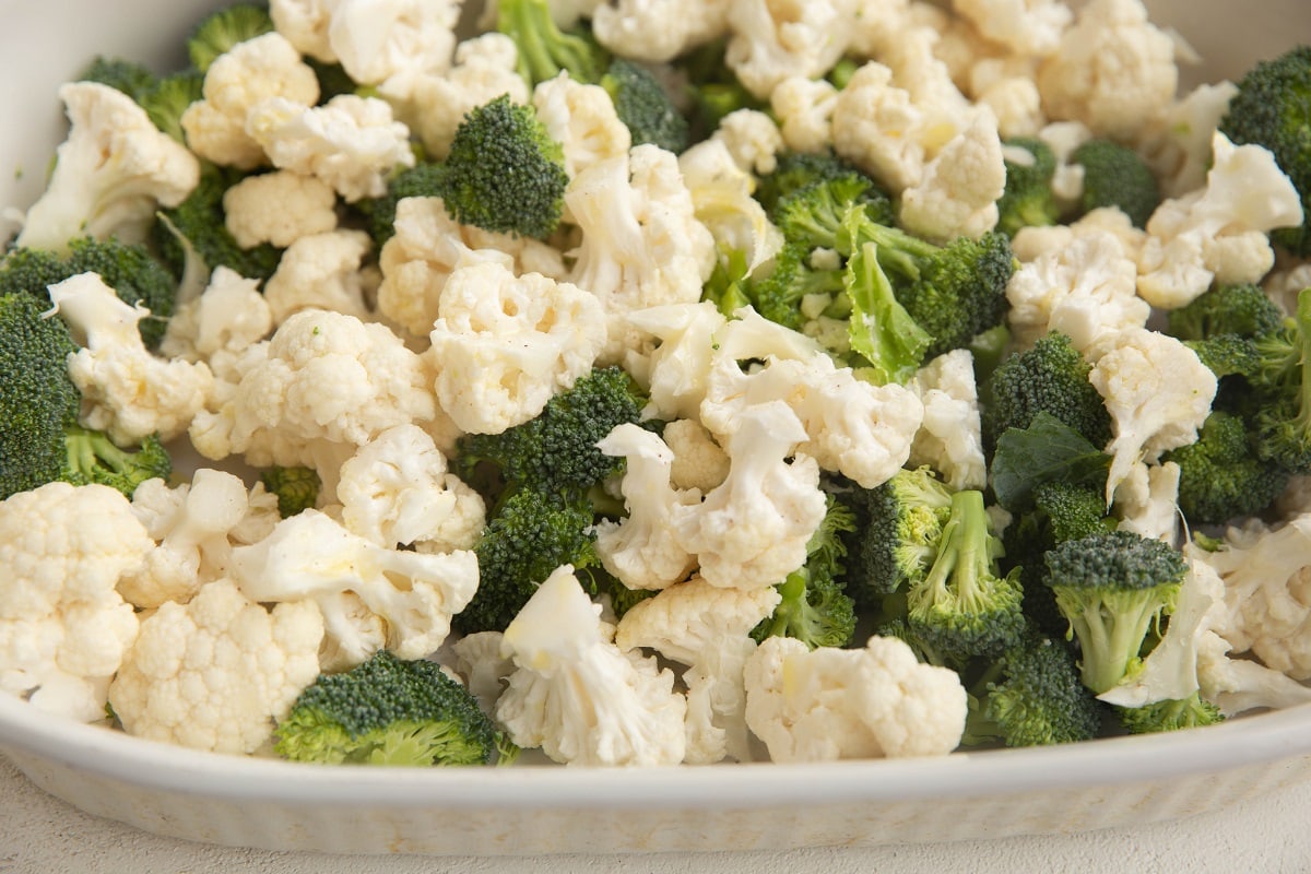 Casserole dish with raw chopped broccoli and cauliflower in it.