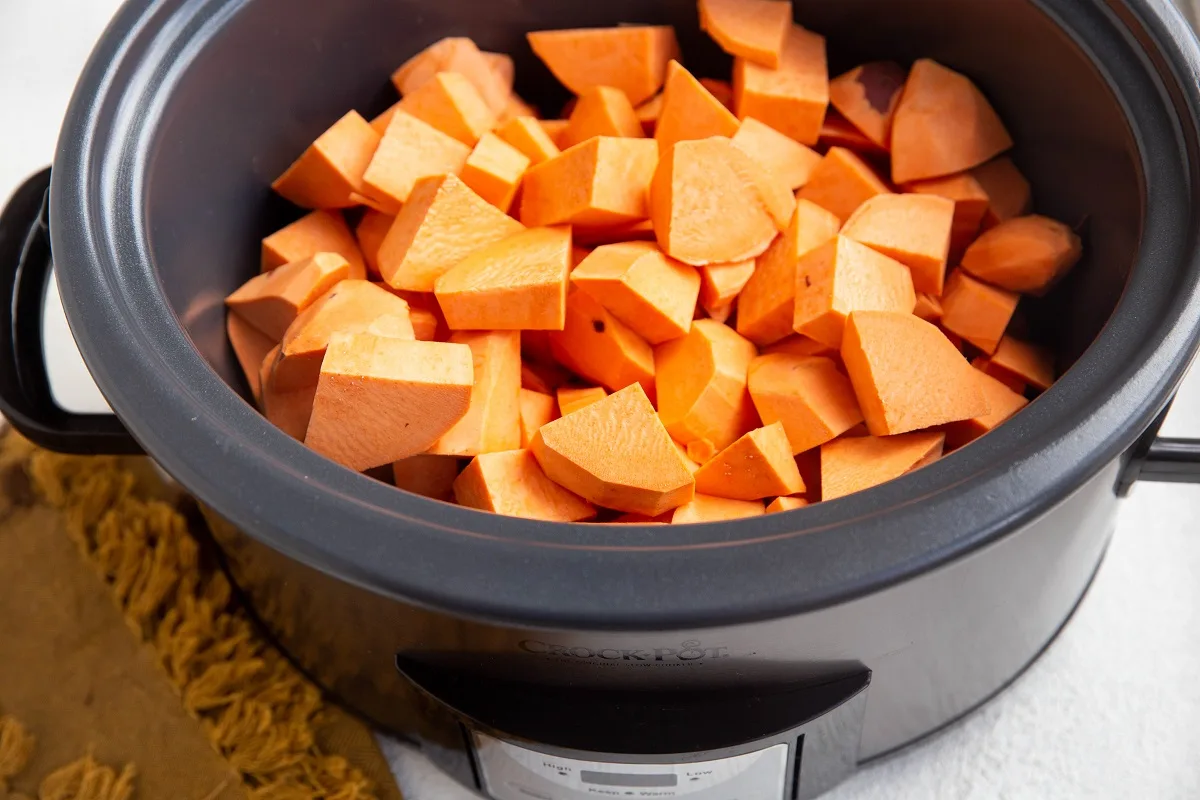Crock pot with chopped sweet potatoes inside.
