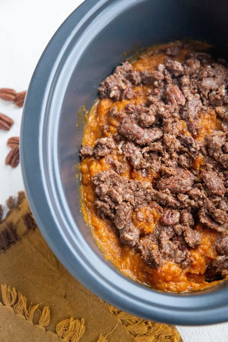 Crock pot filled with sweet potato casserole with delicious pecan topping.