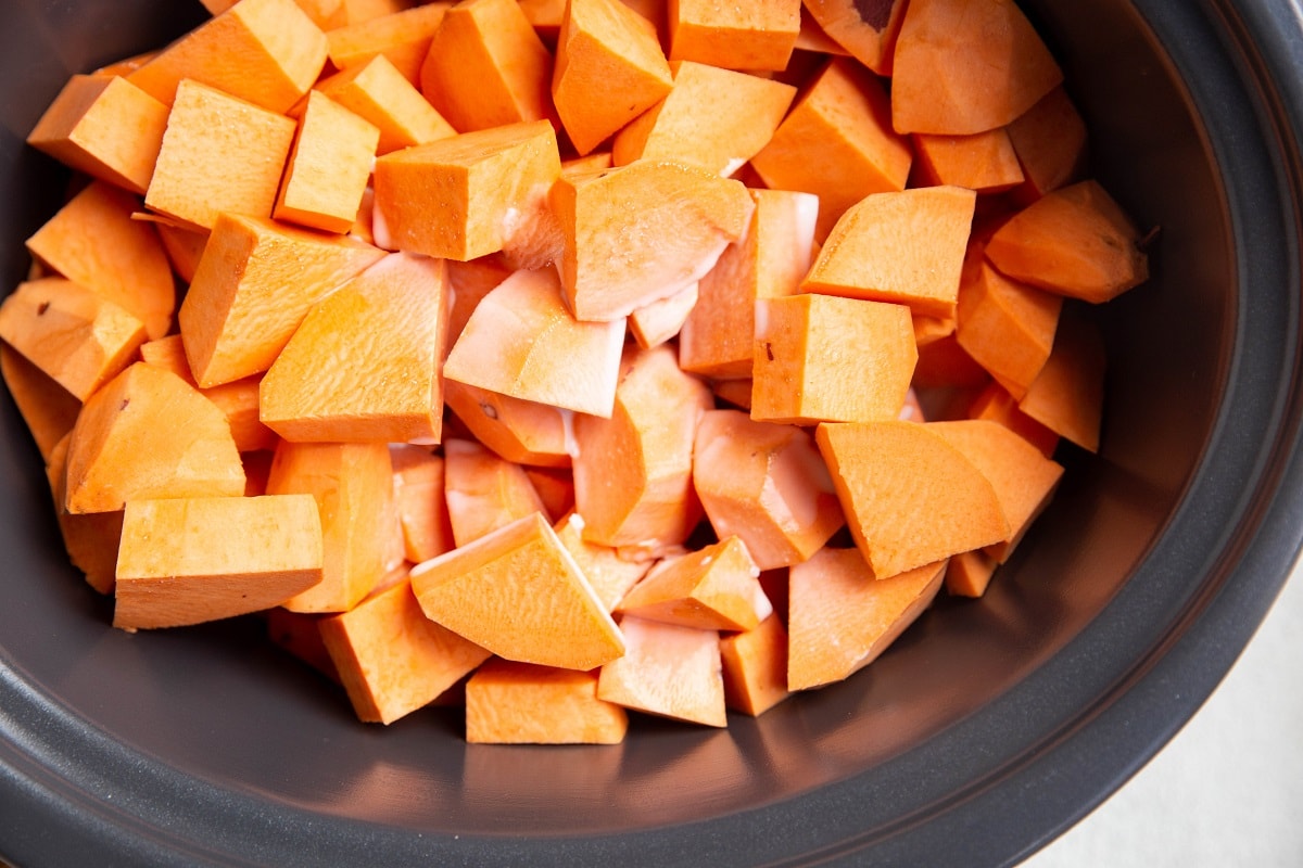 Chopped sweet potatoes with coconut milk inside of a crock pot