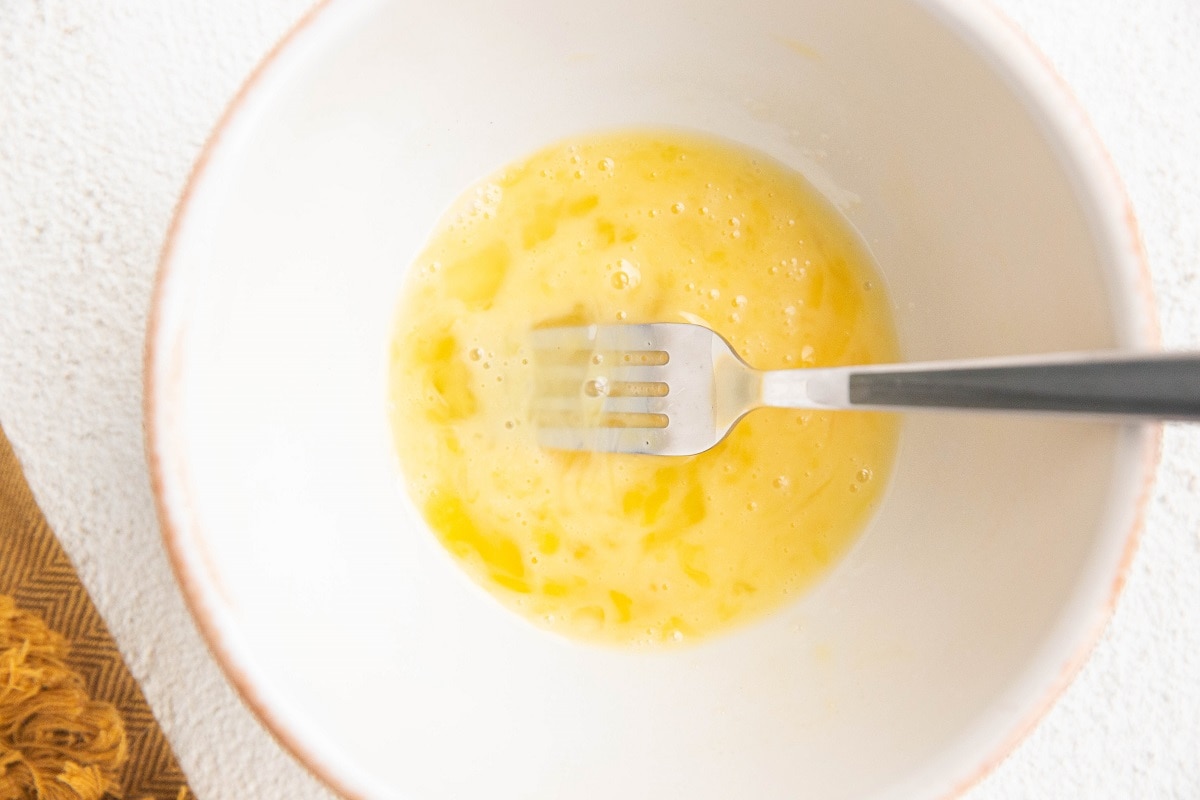 Whisked egg in a white bowl.