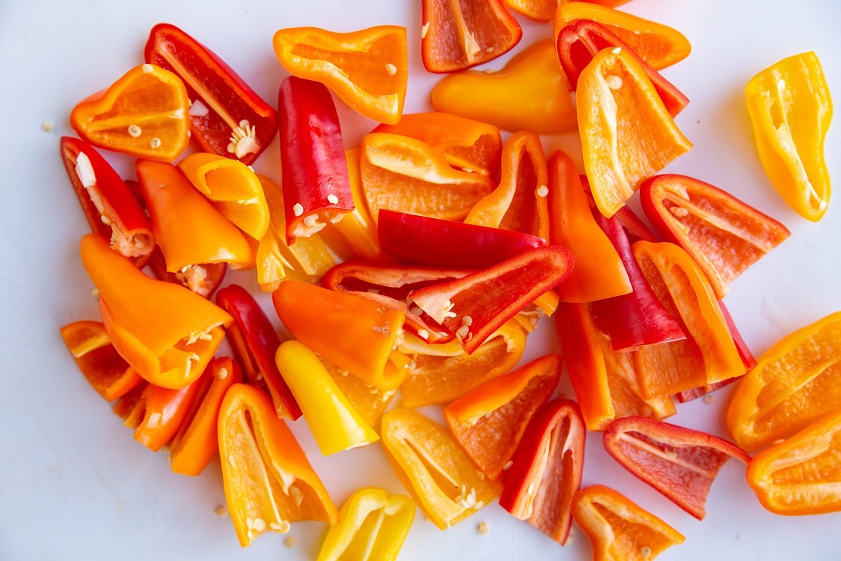 Mini sweet peppers sliced in half on a cutting board