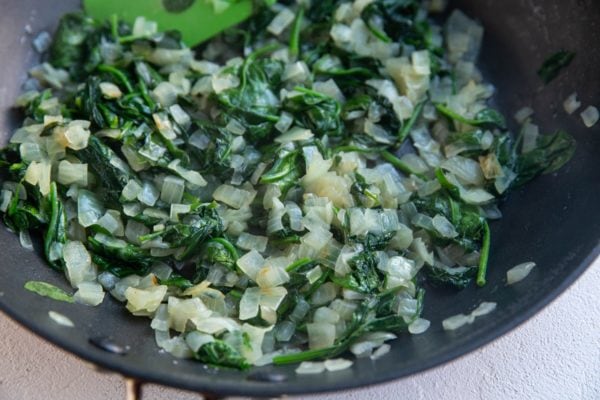 Spinach and onion cooking in a skillet