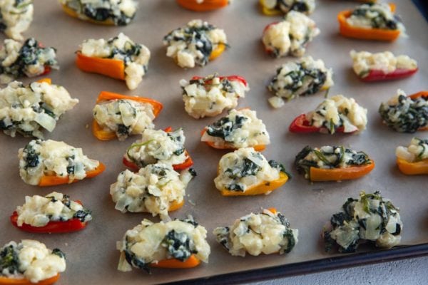 Peppers stuffed with feta and spinach on a baking sheet, ready to bake.