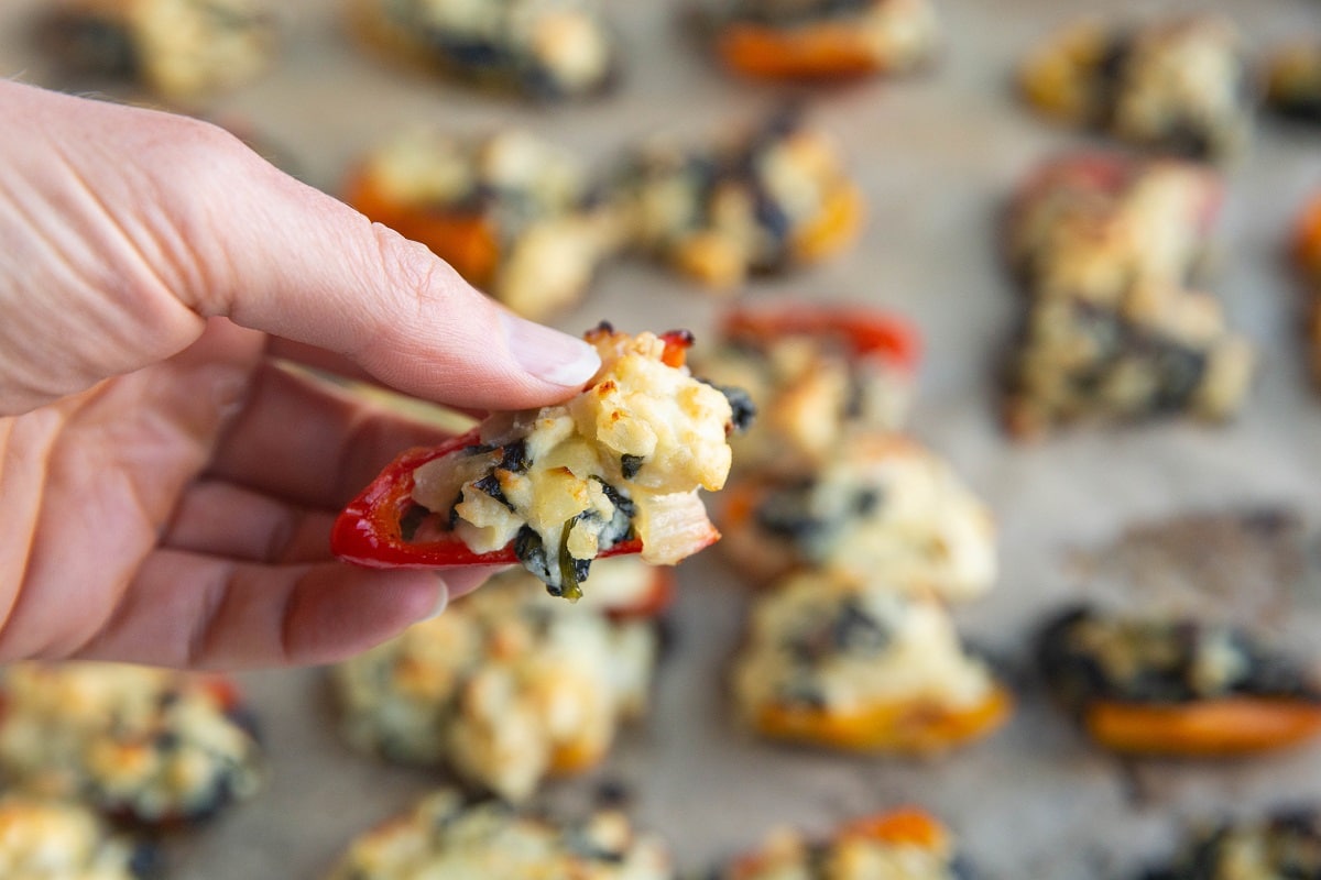 Hand holding a feta and spinach stuffed pepper.