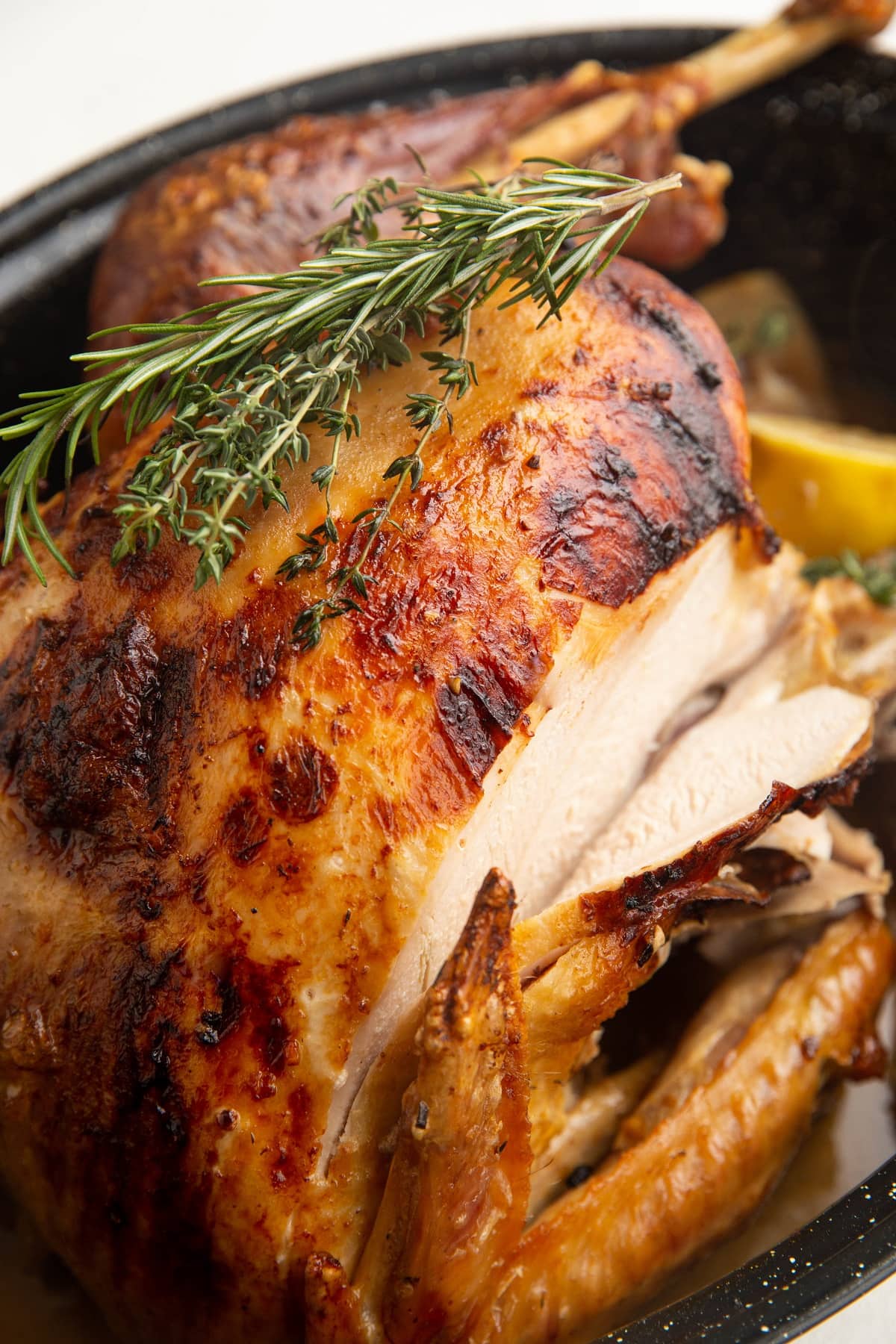Roasted Thanksgiving turkey in a roasting pan with the breast sliced.