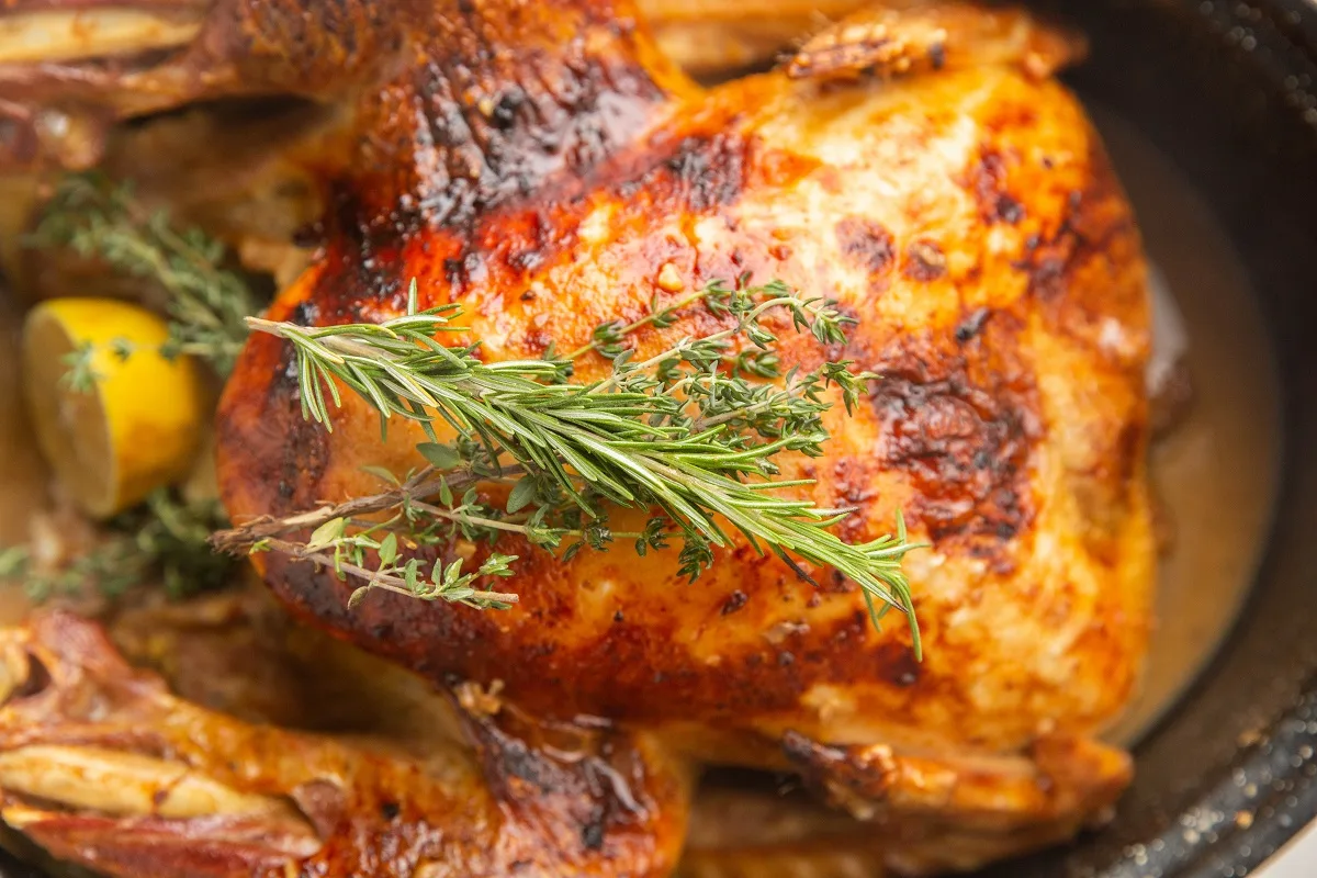 top down horizontal photo of fully cooked turkey with fresh herbs on top.