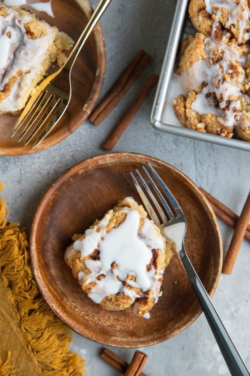 Top down photo of two wooden plates with cinnamon rolls and the pan of cinnamon rolls to the side.