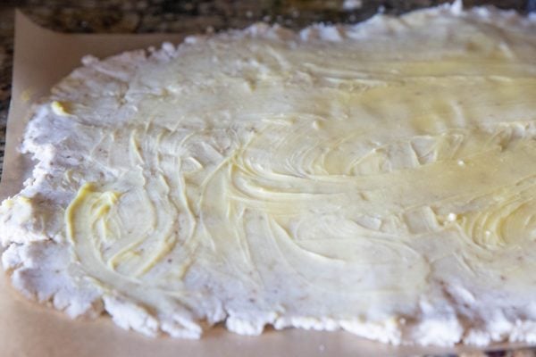 Rolled out dough on parchment paper smeared with butter.