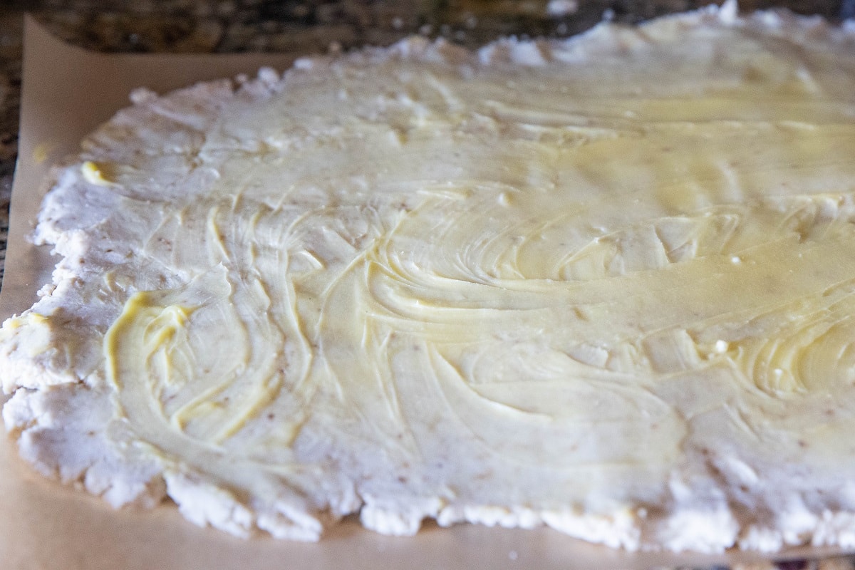 Rolled out dough on parchment paper smeared with butter.