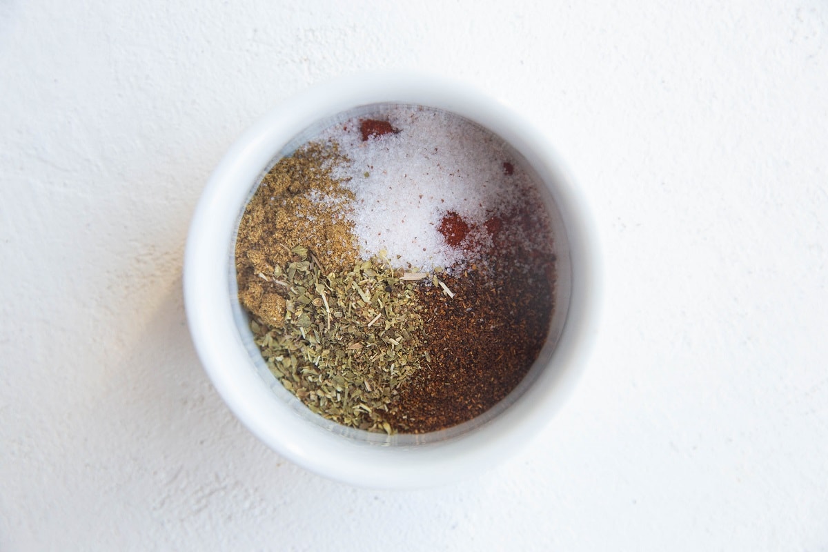 Chili powder, ground cumin, dried oregano, and sea salt in a small bowl to be used in chicken tortilla soup.
