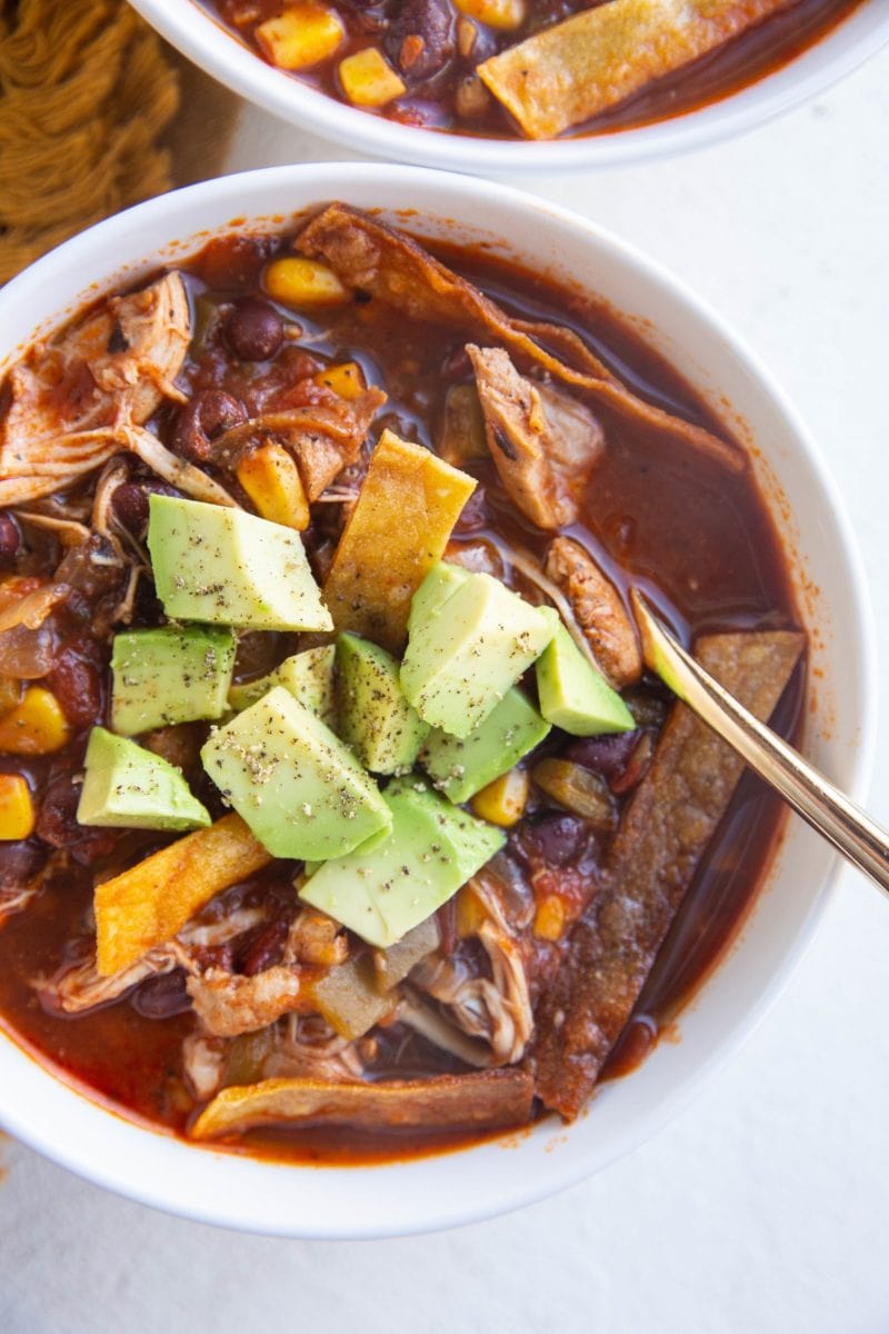 Top down photo of two bowls of chicken tortilla soup.