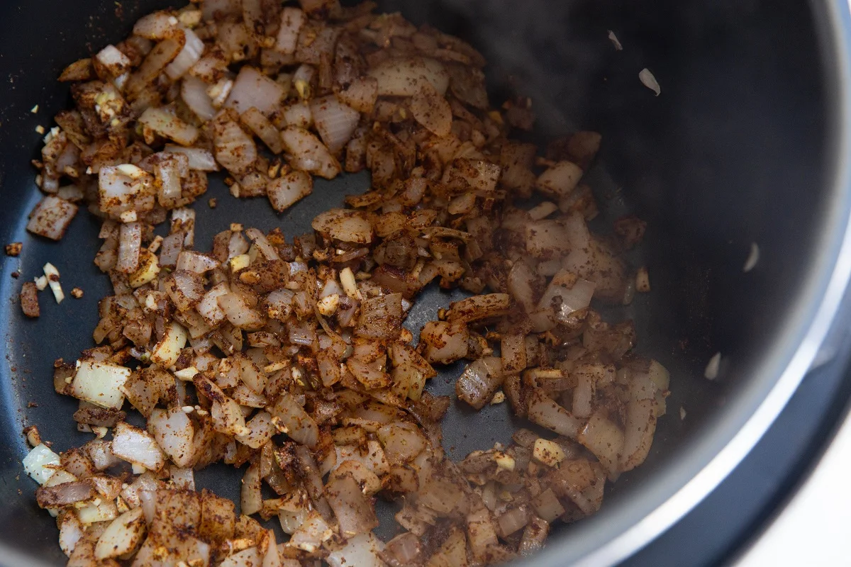 Onions, garlic, and spices cooking in a pressure cooker.