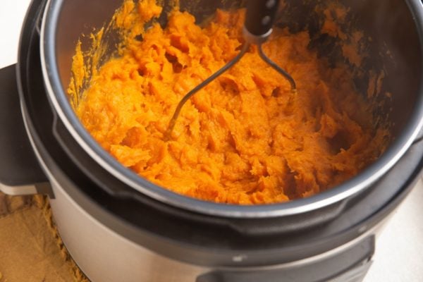 Potato masher mashing the sweet potatoes.