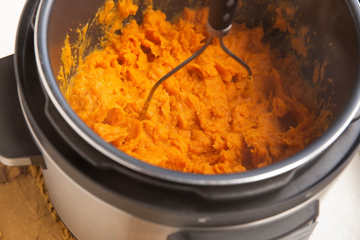 Potato masher mashing the sweet potatoes.