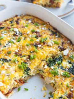 Casserole dish of leftover turkey breakfast casserole with one piece taken out and a plate with a slice of breakfast casserole in the background.