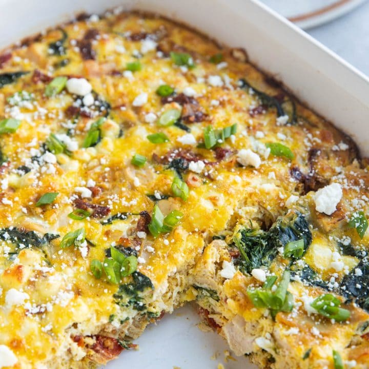 Casserole dish of leftover turkey breakfast casserole with one piece taken out and a plate with a slice of breakfast casserole in the background.
